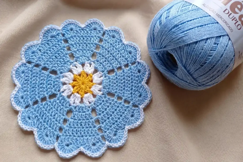 Blue Daisy Crochet Doily Pattern with white scalloped edging and yellow daisy center